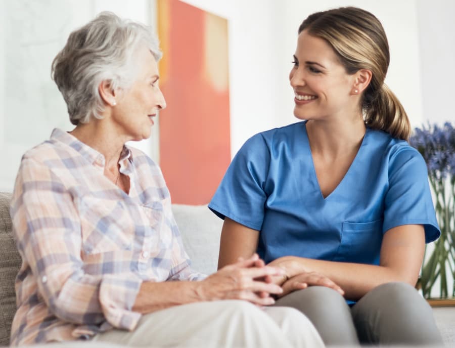 An elderly woman and a nurse seated in pleasant conversation